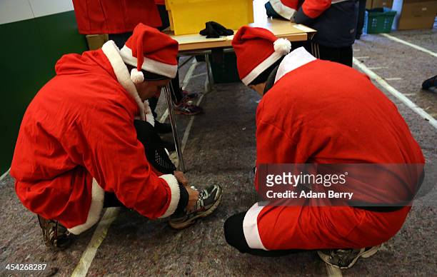 Two participants lace up their shoes as they prepare to compete in the 5th annual Michendorf Santa Run on December 8, 2013 in Michendorf, Germany....