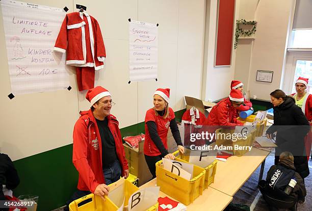 Assistants register visitors competing in the 5th annual Michendorf Santa Run as Santa costumes hang for sale on December 8, 2013 in Michendorf,...