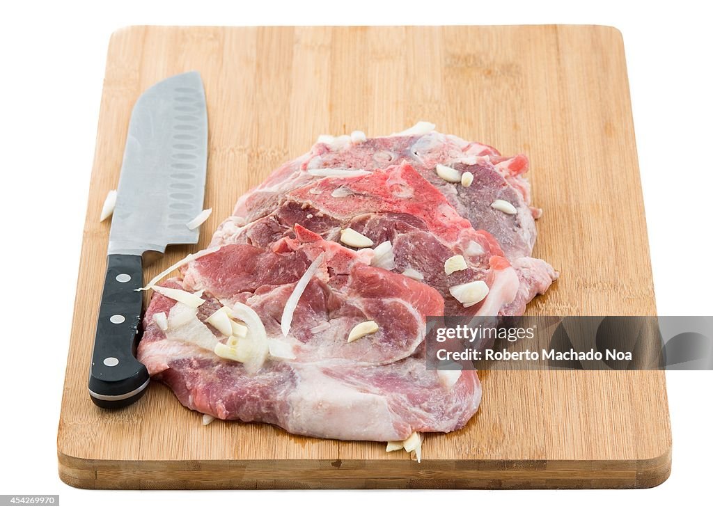 Raw pork sirloin chops marinated over a cutting board with a...