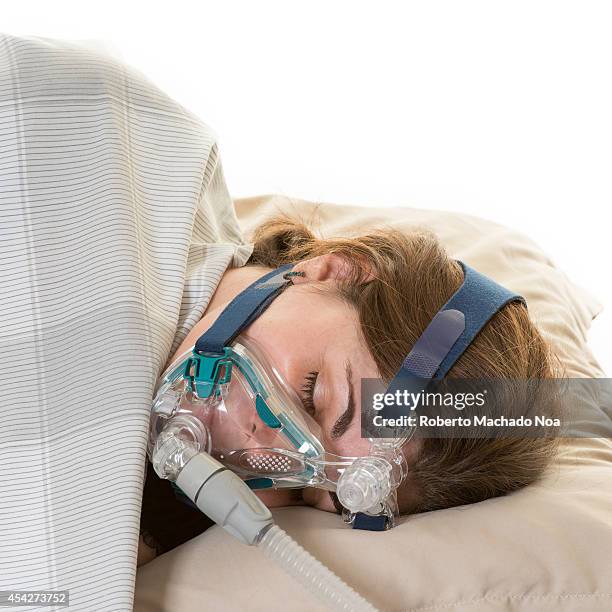 Female wearing the CPAP mask for treating the sleep apnea which is a type of sleep disorder characterized by pauses in breathing or instances of...