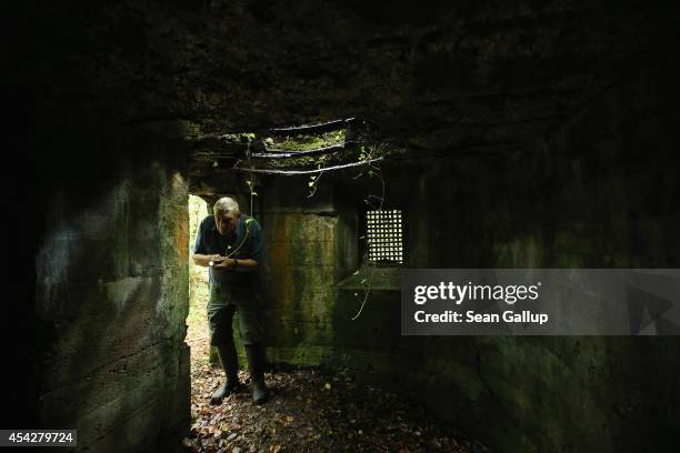 Retired forest services worker Daniel Gadois uses a flashlight to inspect a former World War I German bunker in Spincourt forest on August 27, 2014...