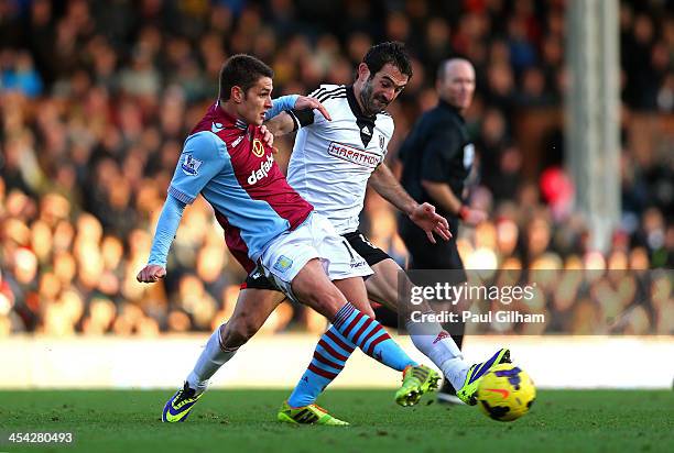 Ashley Westwood of Aston Villa passes the ball under pressure from Giorgos Karagounis of Fulham during the Barclays Premier League match between...