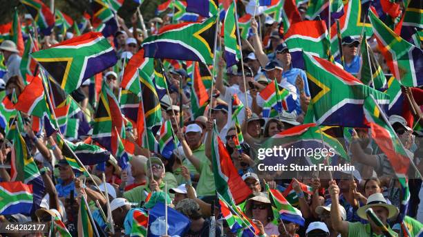 Golf fans wave South African flags in tribute to the late President Nelson Mandela after the final round of the Nedbank Golf Challenge at Gary Player...