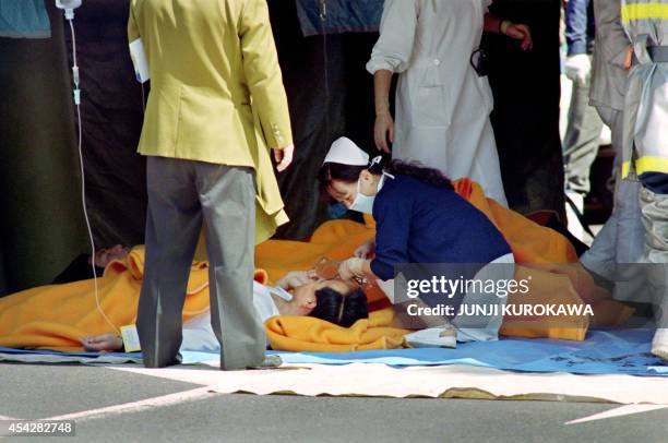 Commuter is treated by an emergency medical team at a make-shift shelter before being transported to hospital after being exposed to Sarin gas fumes...