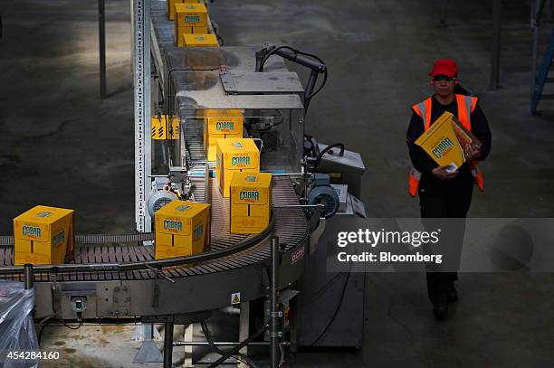 An employee carries a box of Cobra beer, manufactured by Molson Coors Brewing Co., at the company's brewery and bottling plant in Burton-upon-Trent,...