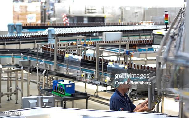 An employee adjusts a filling machine for Coors Light beer, manufactured by Molson Coors Brewing Co., at the company's brewery and bottling plant in...