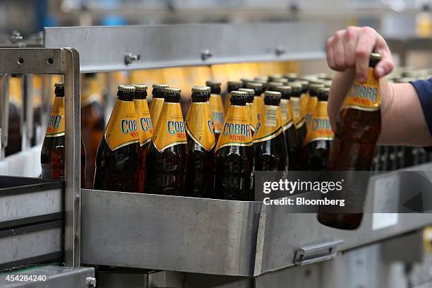 An employee removes a bottle of Cobra beer, manufactured by Molson Coors Brewing Co., from the production line at the company's brewery and bottling...