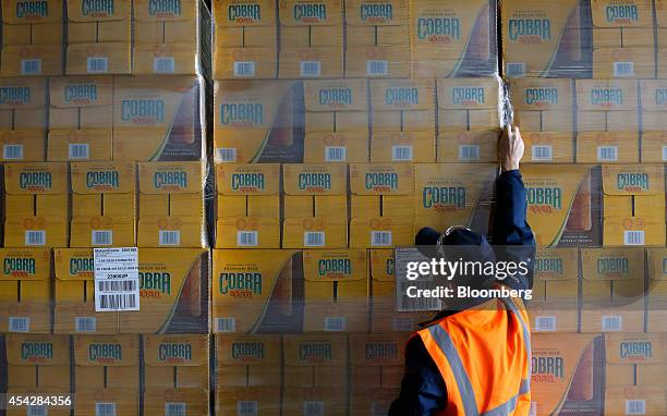 An employee checks the wrapping on boxes of Cobra beer, manufactured by Molson Coors Brewing Co., stored ahead of shipping at the company's brewery...