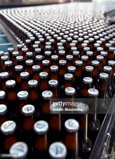 Logos sit on the caps of Coors Light beer bottles, manufactured by Molson Coors Brewing Co., as they move along the production line ahead of labeling...
