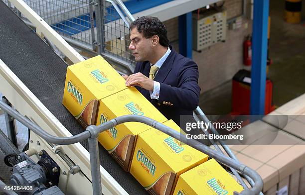 Karan Bilimoria, founder and chairman of Cobra Beer, checks a box of bottled Cobra beer, manufactured by Molson Coors Brewing Co., as it passes along...