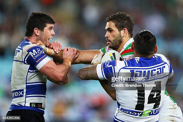 Greg Inglis of the Rabbitohs is tackled by Michael Ennis and Reni Maitua of the Bulldogs during the round 25 NRL match between the Canterbury...
