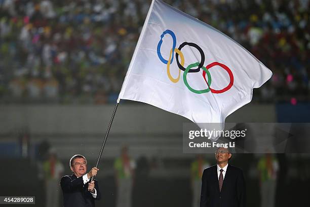 President Thomas Bach waves the Olympic flag after taking it from Nanjing Mayor Mao Ruilin during the closing ceremony for the Nanjing 2014 Summer...