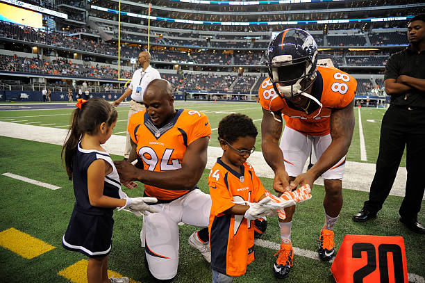 Denver Broncos defensive end DeMarcus Ware puts a glove on his daughters hand Marley and DeMarcus Jr. Gets a glove from Denver Broncos wide receiver...