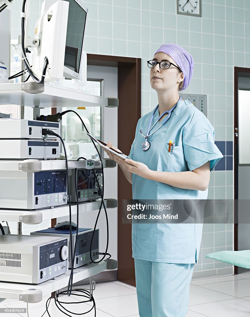 Surgeon using digital tablet, watching monitor