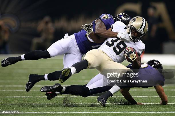 Travaris Cadet of the New Orleans Saints is tackled by Justin Tucker of the Baltimore Ravens and Sammy Seamster of the Baltimore Ravens in their pre...
