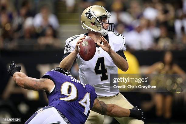 Ryan Griffin of the New Orleans Saints throws a pass under pressure from John Simon of the Baltimore Ravens in their pre season game at the...