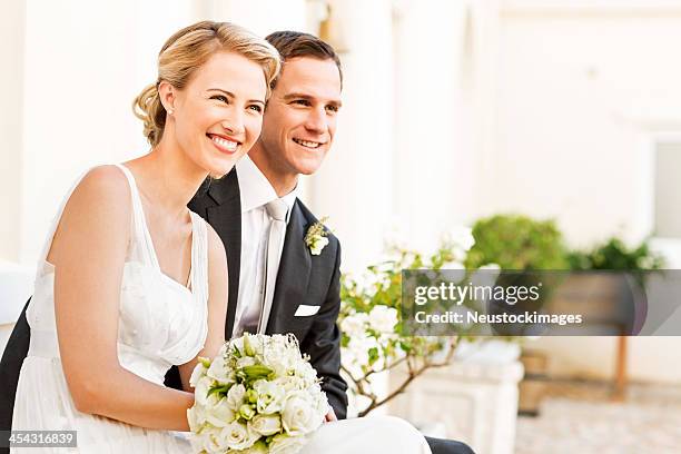 bride and groom with flower bouquet looking away - bride and groom stockfoto's en -beelden