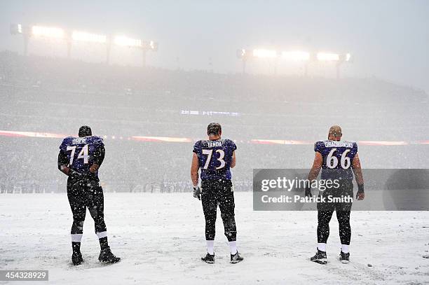 Tackle Michael Oher, guard Marshal Yanda and center Gino Gradkowski of the Baltimore Ravens stand on the snow covered field during the national...