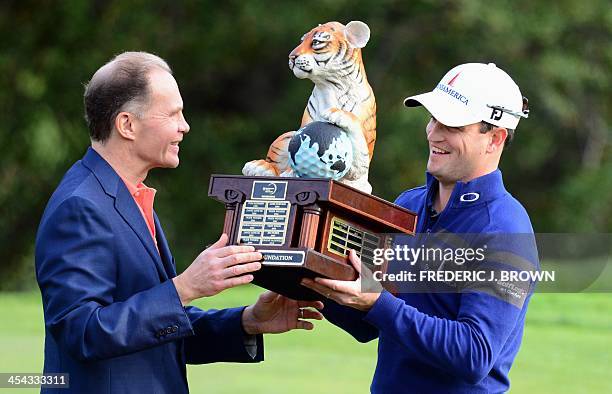 Golfer Zach Johnson is awarded the championship trophy after the final round of play to win the Northwestern Mutual World Challenge golf tournament...