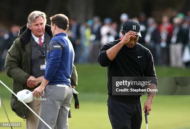 Tigers Woods walks off the green as Zach Johnson is congrtulated by PGA Tour rules official Mark Russell after Johnson defeated Woods on the first...