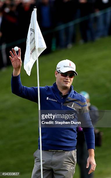 Zach Johnson holds up his ball after holing out from the drop zone after going in the water on the 18th hole to force a playoff during the final...