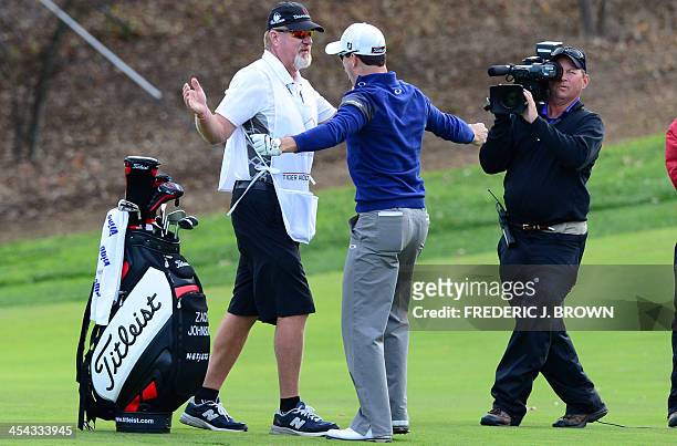 Golfer Zach Johnson and his caddy celebrate after Johnson's shot to the green during the playoff against Tiger Woods after the final round of play to...