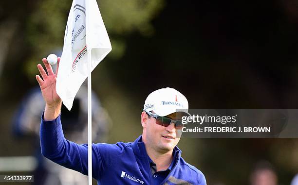 Golfer Zach Johnson gestures to the crowd after sinking his putt on the green during the playoff against Tiger Woods after the final round of play to...