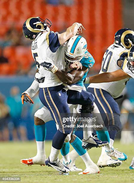 Dion Jordan of the Miami Dolphins hits Garrett Gilbert of the St. Louis Rams as he releases the ball in the fourth quarter during a preseason game on...