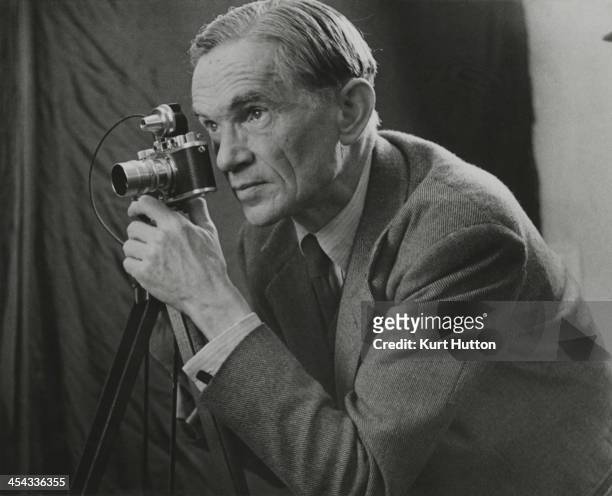 German-born photographer Kurt Hutton using a tripod-mounted Leica camera, circa 1950.