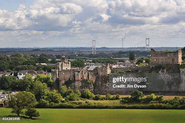 View looking across the River Wye to the clifftop ruins of Chepstow Castle, as the Severn suspension Bridge to England rises in the background, on...