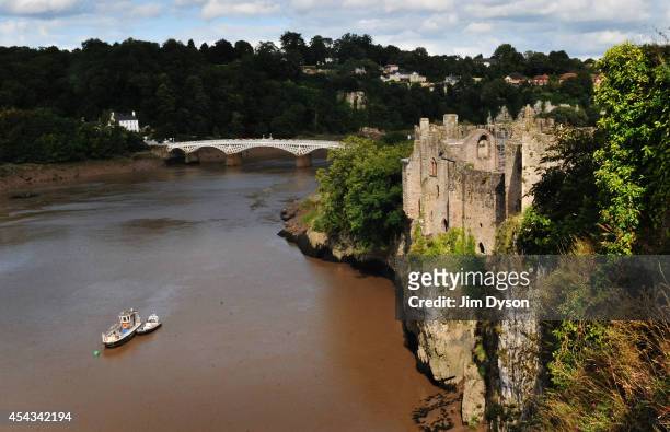 View looking across the River Wye towards the clifftop ruins of Chepstow Castle, with the Old Wye Bridge to Gloucestershire, England in the...