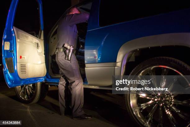 Vice squad officer with the Los Angeles Police Department checks the contents of a car driven by a man suspected of being a pimp February 1, 2013...