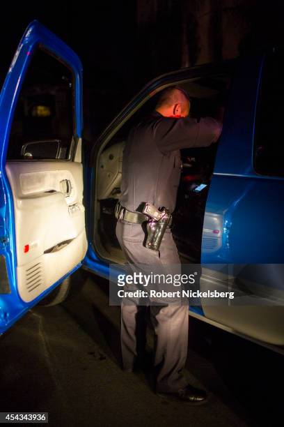 Vice squad officer with the Los Angeles Police Department checks the contents of a car driven by a man suspected of being a pimp February 1, 2013...