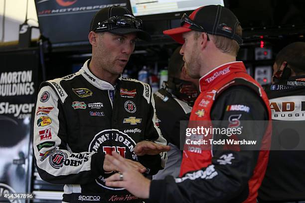 Kevin Harvick , driver of the Bad Boy Buggies Chevrolet, talks to Regan Smith, driver of the TaxSlayer Bowl Chevrolet, in the garage area during...