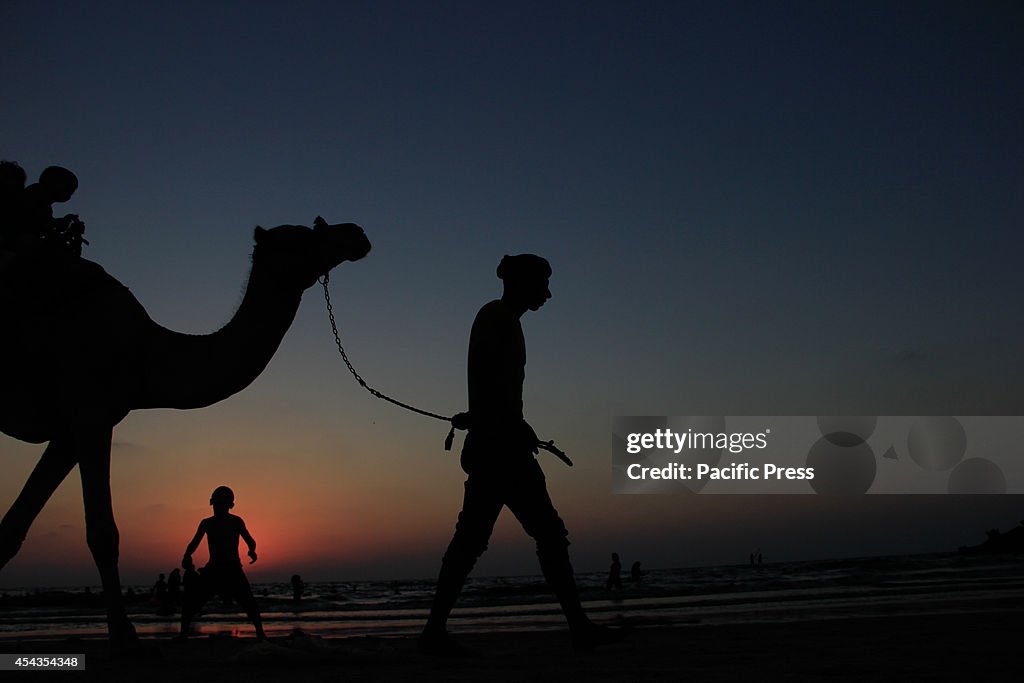 Kids are given camel rides on the beach as Palestinians...