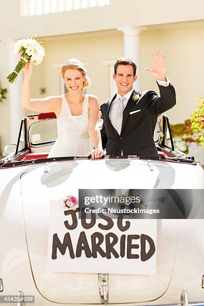 happy just married couple waving in car - just married car stockfoto's en -beelden