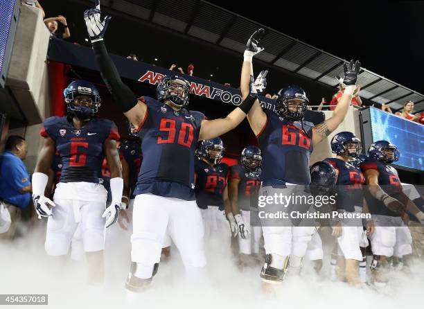 Jonathan McKnight, Dan Pettinato and Mickey Baucus of the Arizona Wildcats prepare to take the field with teammates before the college football game...