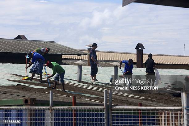 Residents clean ash from their rooftops following the eruption of Mount Tavurvur in eastern Papua New Guinea on August 30, 2014. A volcano which has...