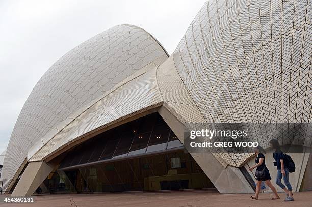 Tourists walk past the sails of Sydney's iconic Opera House building on December 9, 2013 including the tallest sail , known as A2, which covers the...