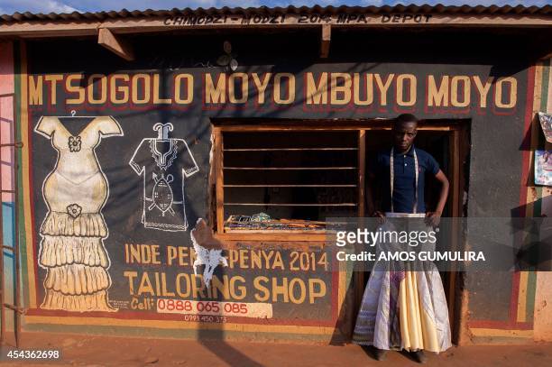 James Kasimu Banda tries to wear a client's skirt which he made in his tailoring shop 'MTSOGOLO MOYO MBUYO MOYO' on August 14 at the Thanki Market of...