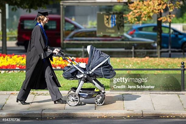 Graduate in gown and caps push after their graduation at the HHL Leipzig Graduate School of Management a baby carriage on August 30, 2014 in Leipzig,...