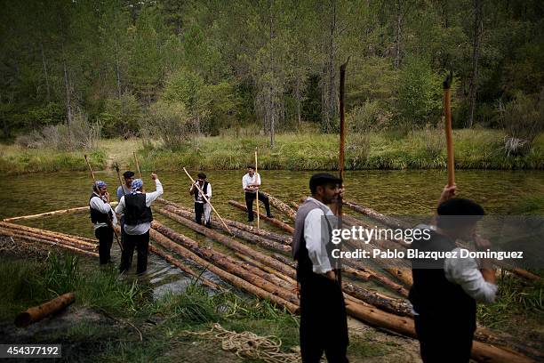 Revellers dressed as 'Gancheros' wait to take out logs from the Tajo River during the 'Gancheros' festival on August 30, 2014 in Poveda de la Sierra,...