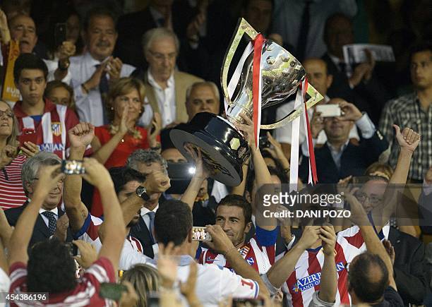 Atletico Madrid's midfielder and captain Gabi carries the 2013-2014 Spanish Liga Champions trophy before the Spanish league football match Club...