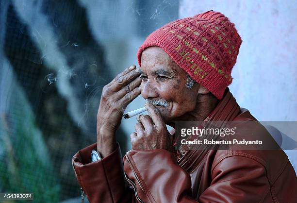Dieng old native man smokes as he watch the Dieng Cultural Festival 2014 on August 30, 2014 in Dieng, Java, Indonesia. The Dieng Culture Festival is...