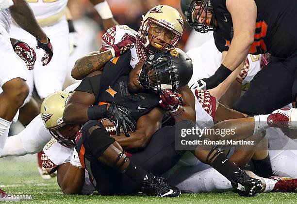 Desmond Roland of the Oklahoma State Cowboys is tackled by the Florida State Seminoles defense in the first half of the Advocare Cowboys Classic at...