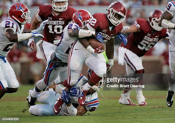 Running back Samaje Perine of the Oklahoma Sooners is tackled by defensive back Kentrell Brice and defensive lineman Andre Taylor of the Louisiana...