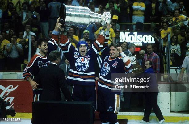 Mark Messier of the Edmonton Oilers hoists the Stanley Cup over his head and shouts as he and teammates Kevin Lowe and Jari Kurri celebrate after...