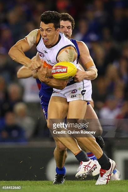 Dylan Shiel of the Giants handballs whilst being tackled by Tom Liberatore of the Bulldogs during the round 23 AFL match between the Western Bulldogs...