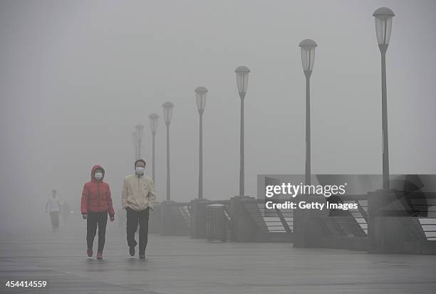 People wearing masks walk along The Bund on December 8, 2013 in Shanghai, China. Heavy smog has been lingering in northern and eastern parts of China...