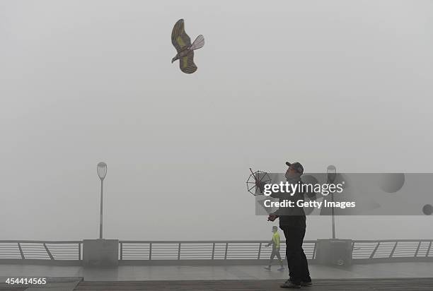 Man flies a kite at The Bund on December 8, 2013 in Shanghai, China. Heavy smog has been lingering in northern and eastern parts of China since last...